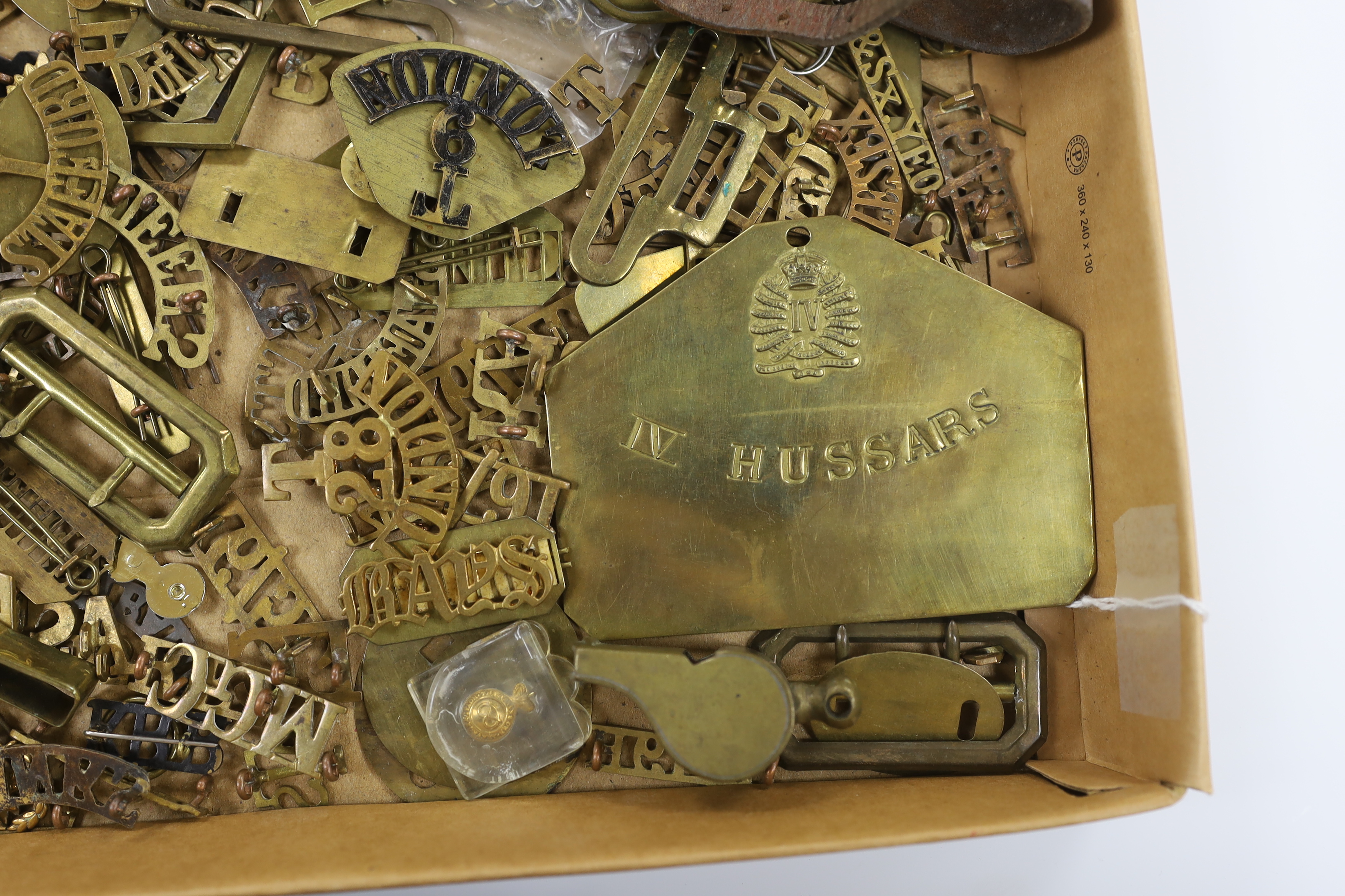 A collection of military cap badges, shoulder titles, pins, backing plates, belt buckles, etc.
